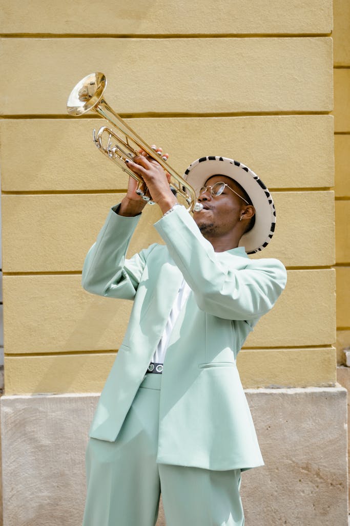 A stylish street musician passionately plays the trumpet outdoors.